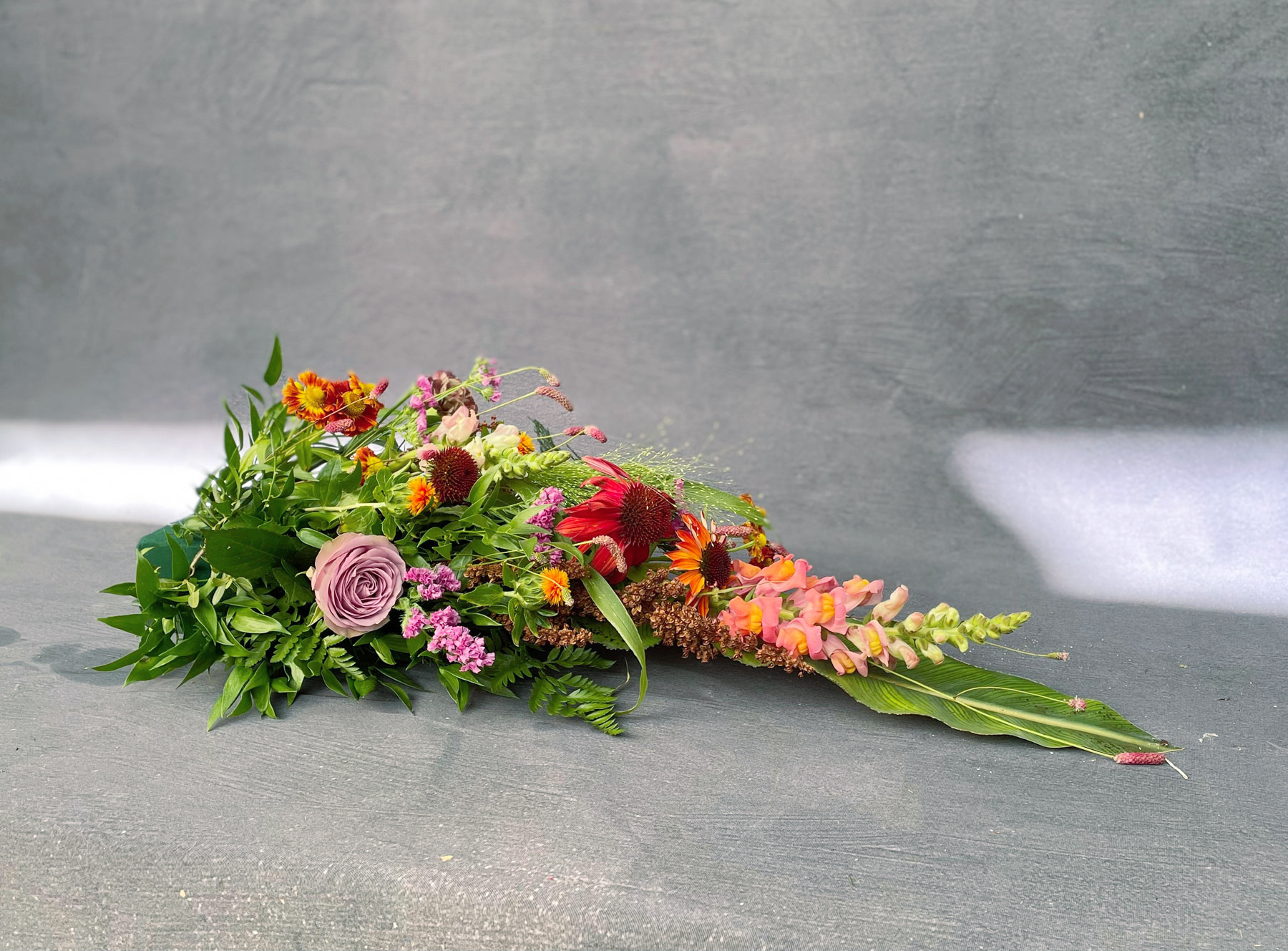 Begravelsespude bundet med blomster i stærke multifarver hos Acacia Blomsterkunst. 