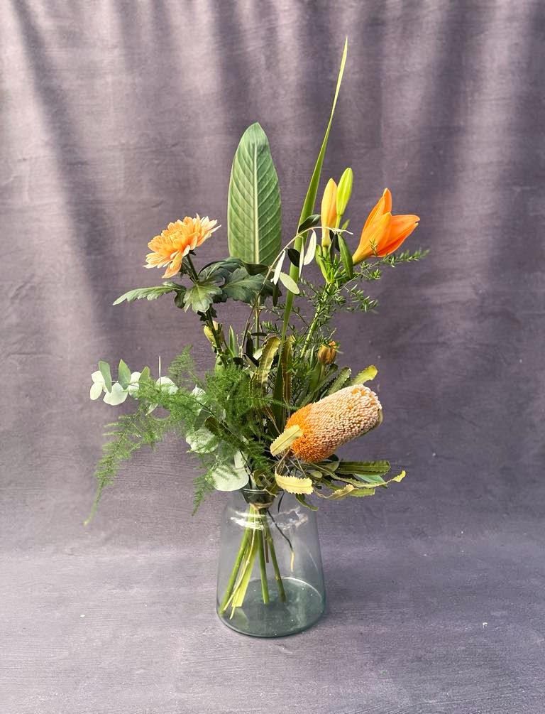 Høj og luftig buket i varme, orange og grønne farver. 