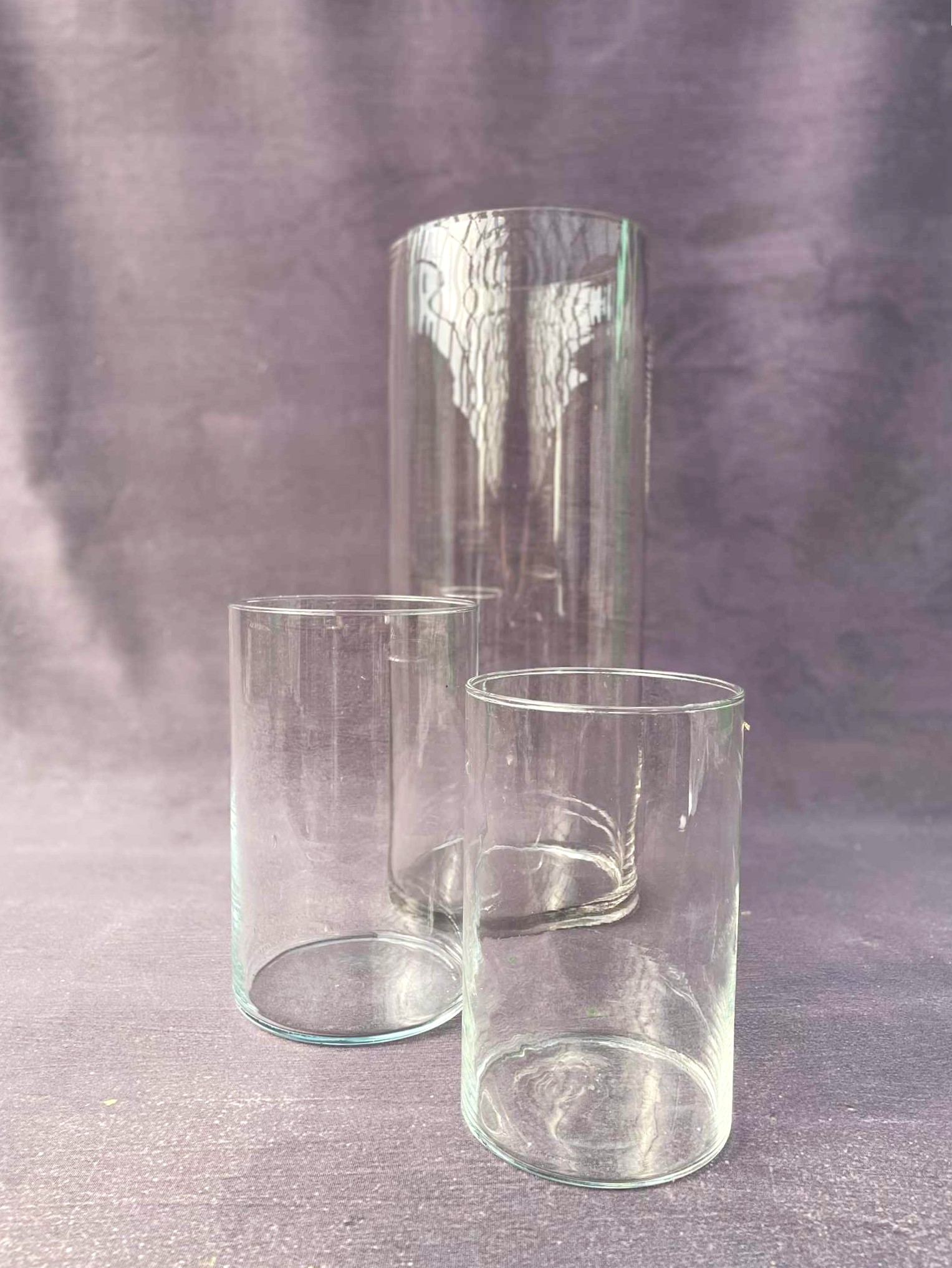 Glasvaser i forskellige størrelser står opstillet ved en grå baggrund hos Acacia Blomsterkunst. 