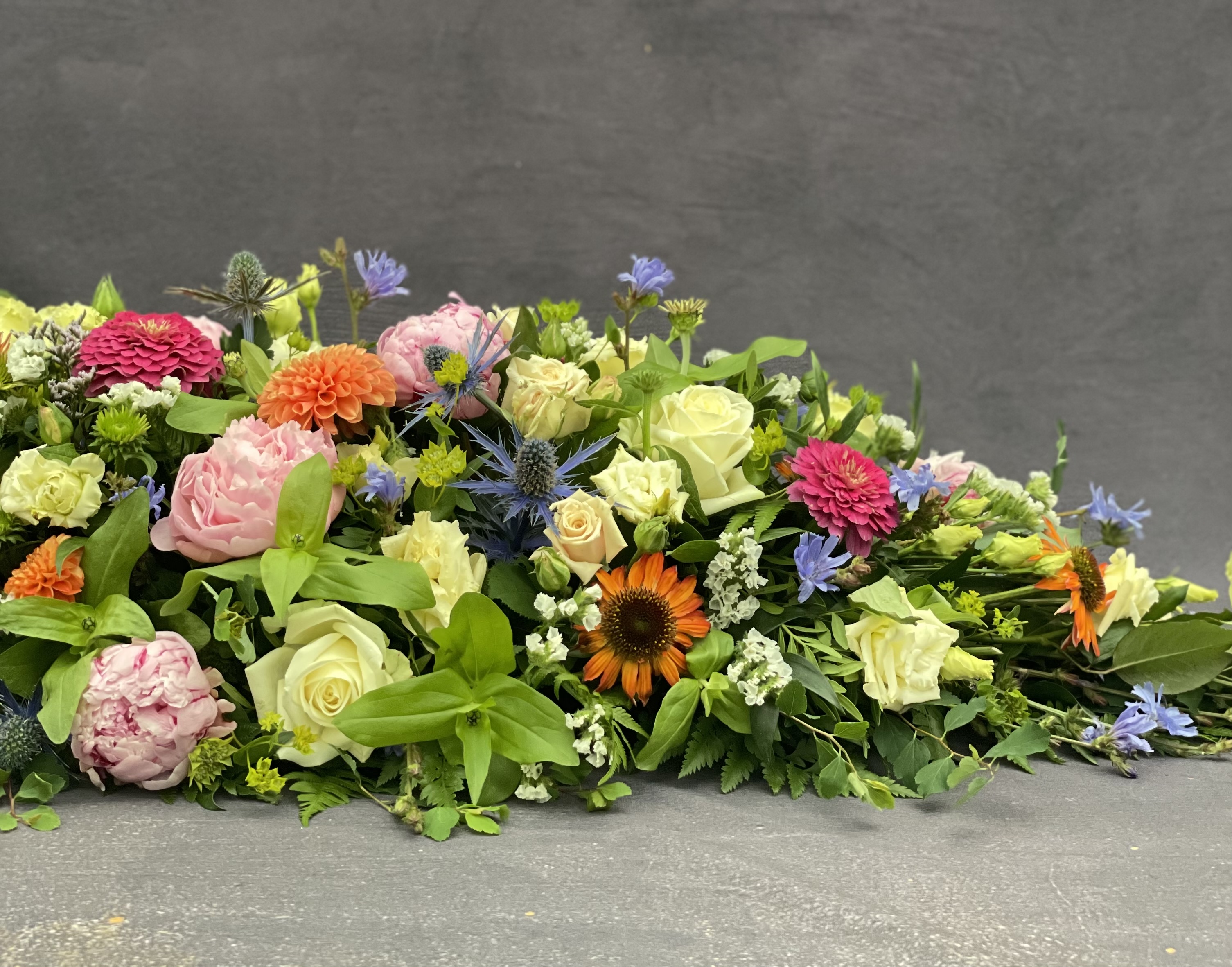 Kistepynt bundet med friske og farverige blomster i et naturligt og livligt udtryk. 