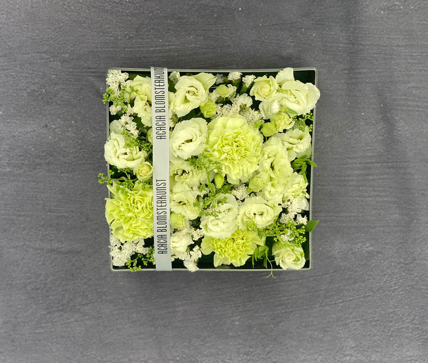 Signatur box med blomster sat tæt i en firkantet æske. Den er lavet med blomster i hvide nuancer. 