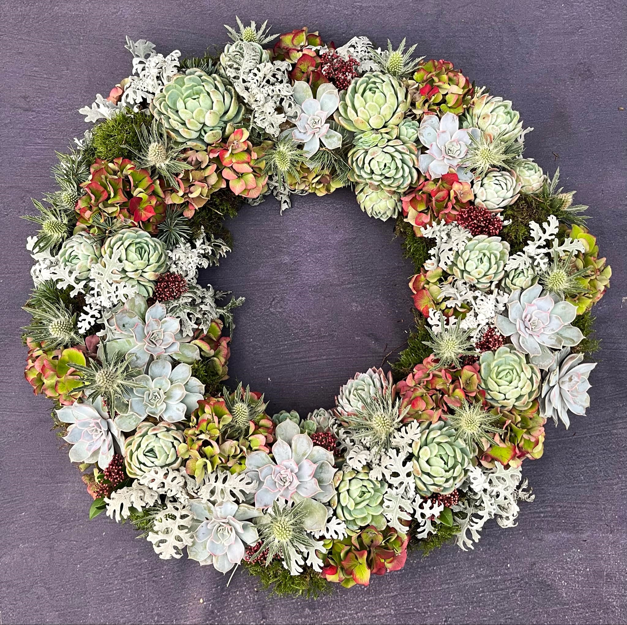 Krans spækket med smukke naturmaterialer, som husløg, mandstro, hortensia og blandet grønt.