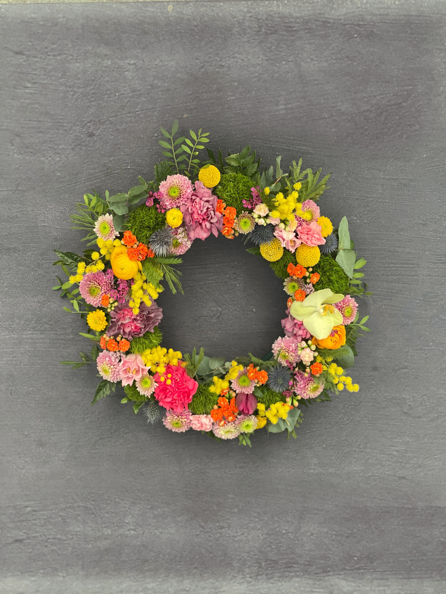 Begravelseskrans bundet med forårets farverige blomster. 