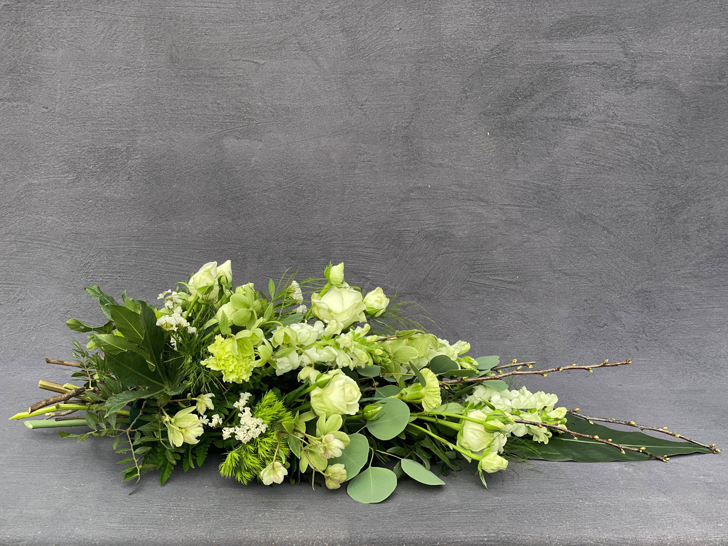 Bårebuket bundet med hvide blomster, eukalyptus og vintergrønt. 